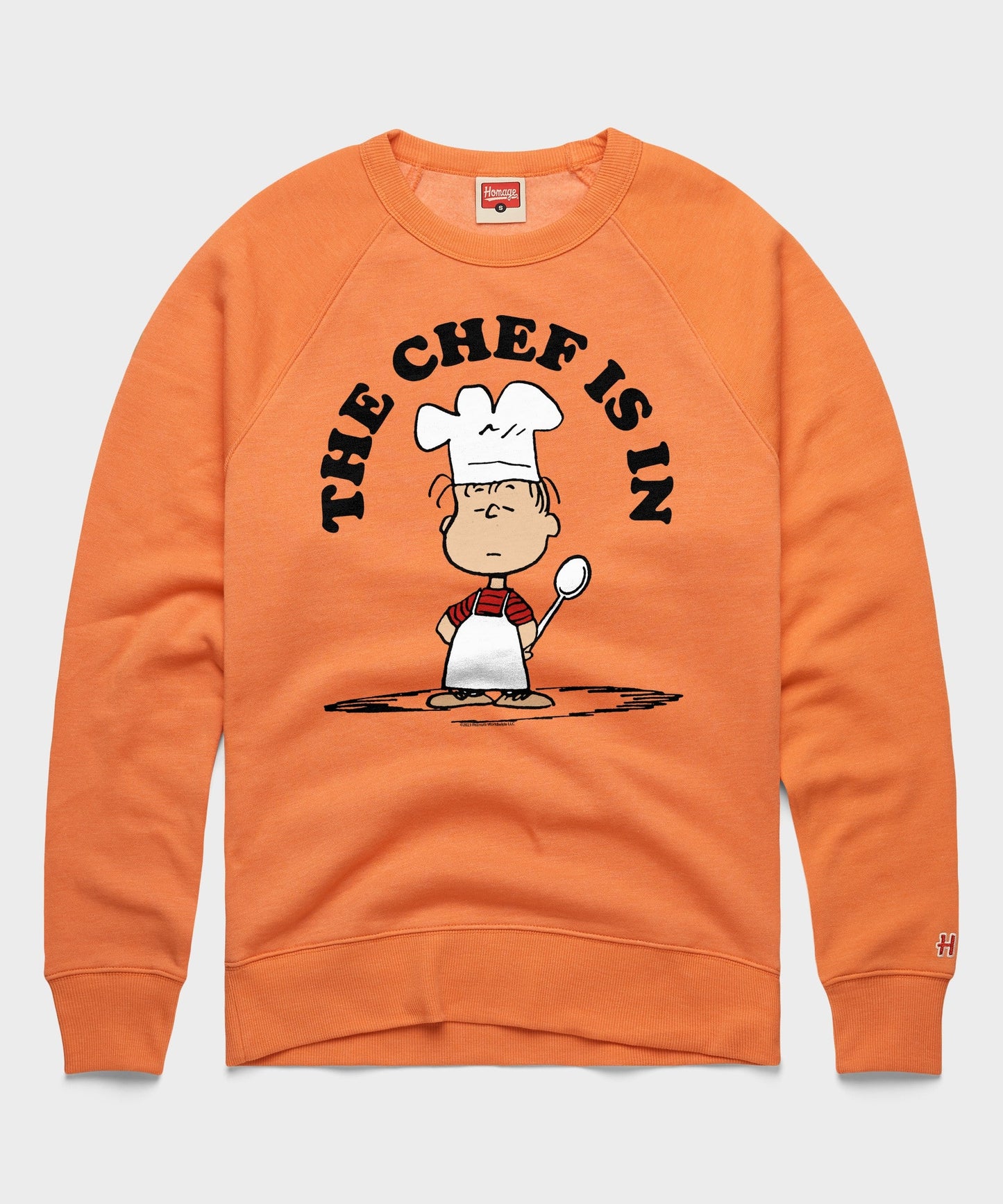 Orange crewneck sweatshirt featuring Linus van Pelt with a chef hat and apron on the front
