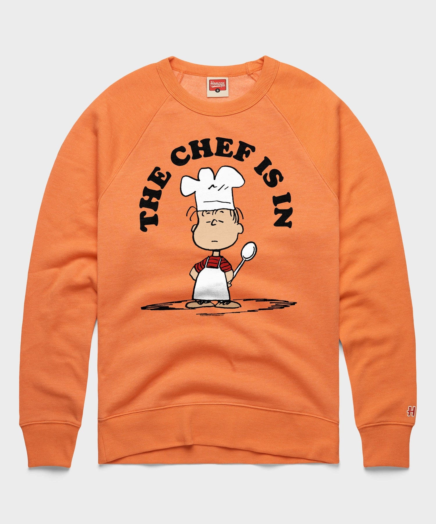 Orange crewneck sweatshirt featuring Linus van Pelt with a chef hat and apron on the front