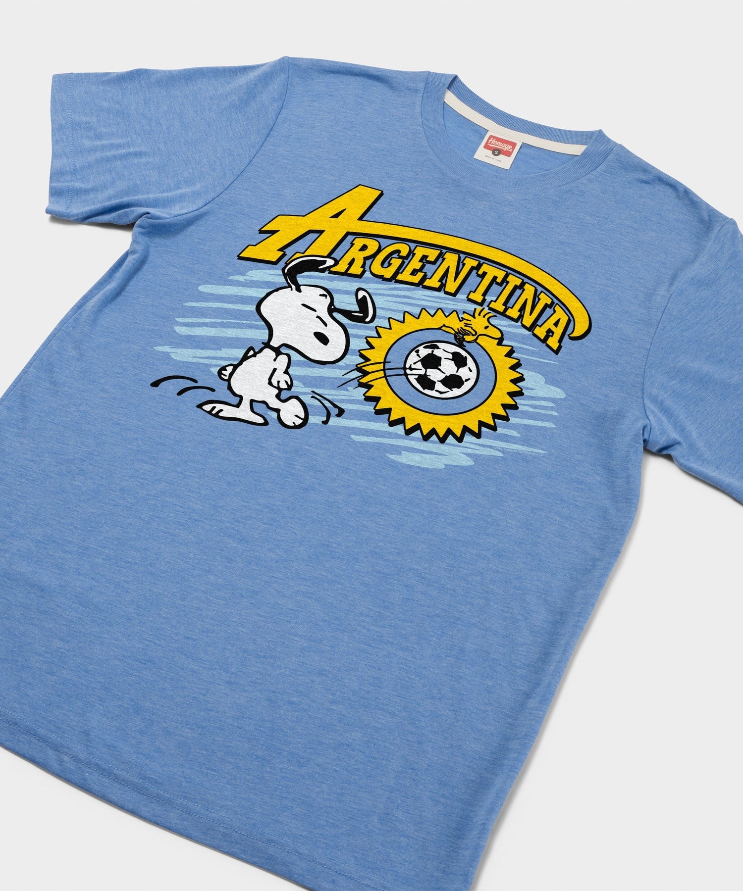Close-up of the screen-printed Snoopy soccer graphic on the front of the light blue t-shirt