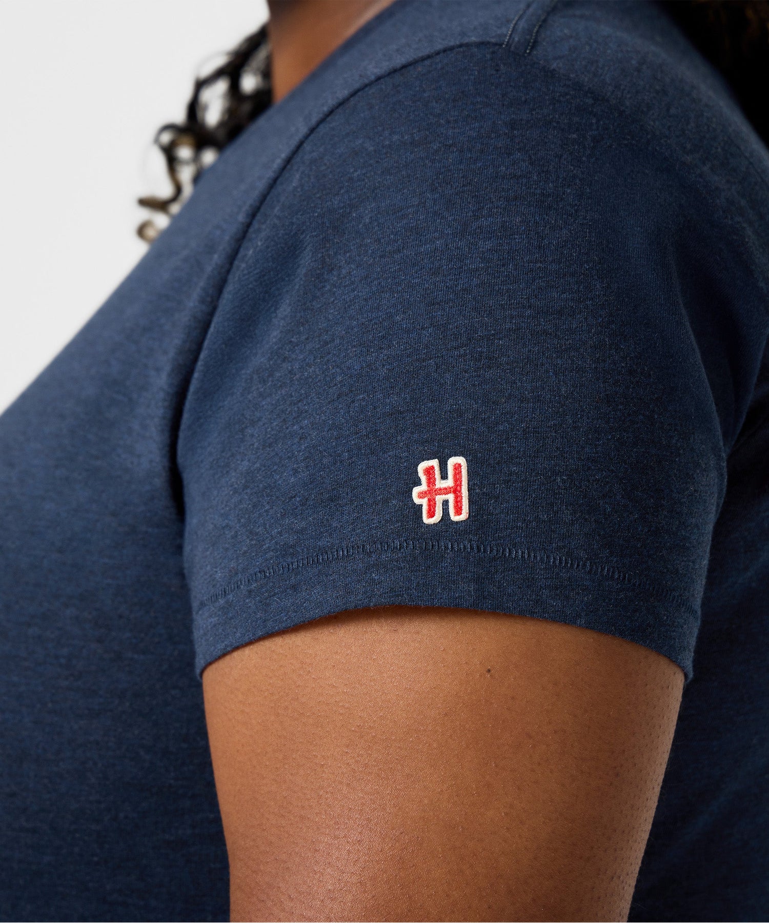 Folded navy t-shirt showing the collaborative HOMAGE brand tag on the hem
