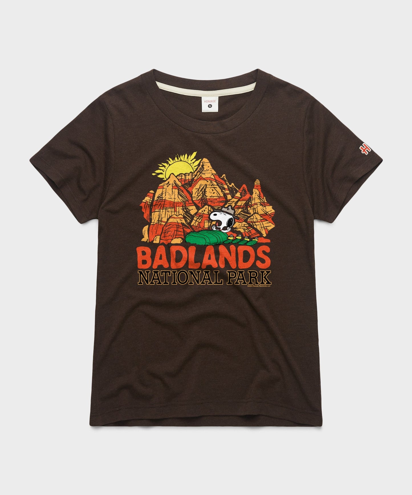 Brown women's t-shirt with a graphic of Snoopy resting near Badlands National Park on the chest