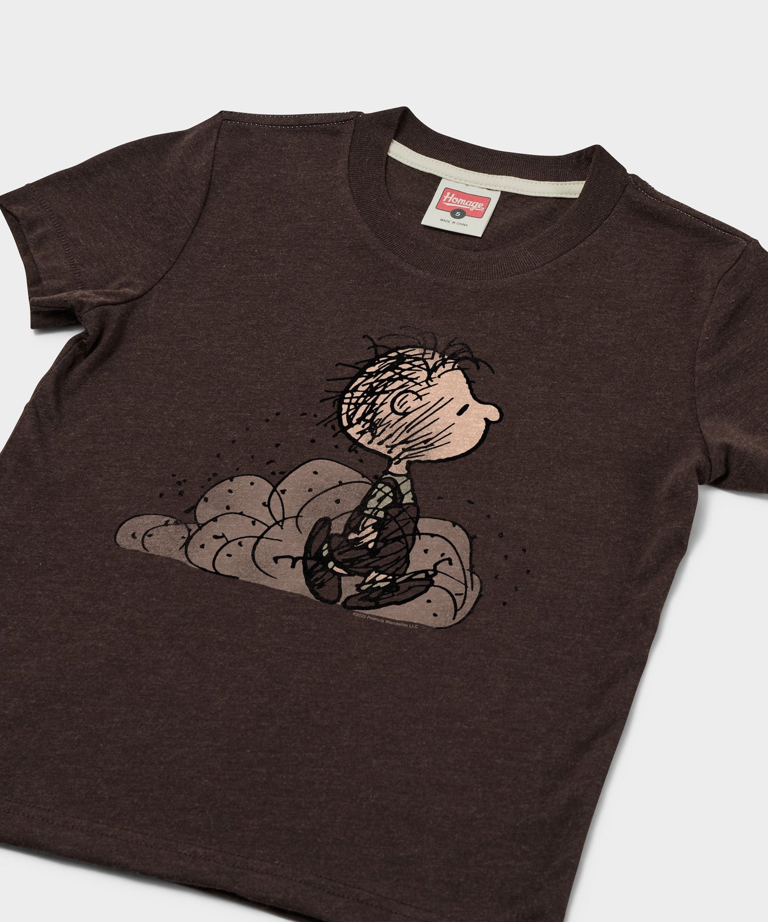 Close-up of the graphic print showing Pig-Pen with his signature dirt cloud on the brown fabric