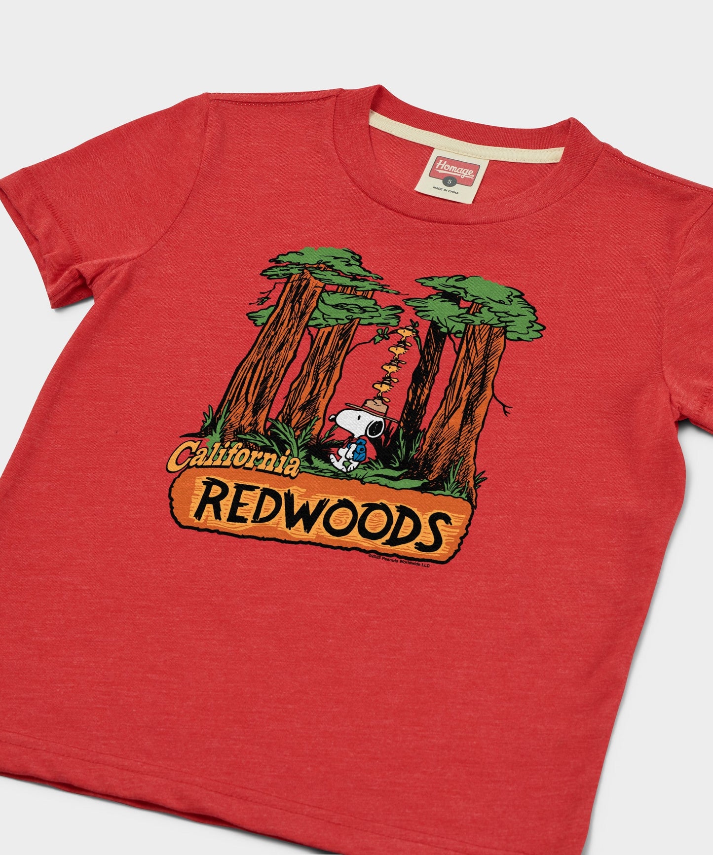 Close-up of the graphic on the red youth t-shirt showing Snoopy in the forest