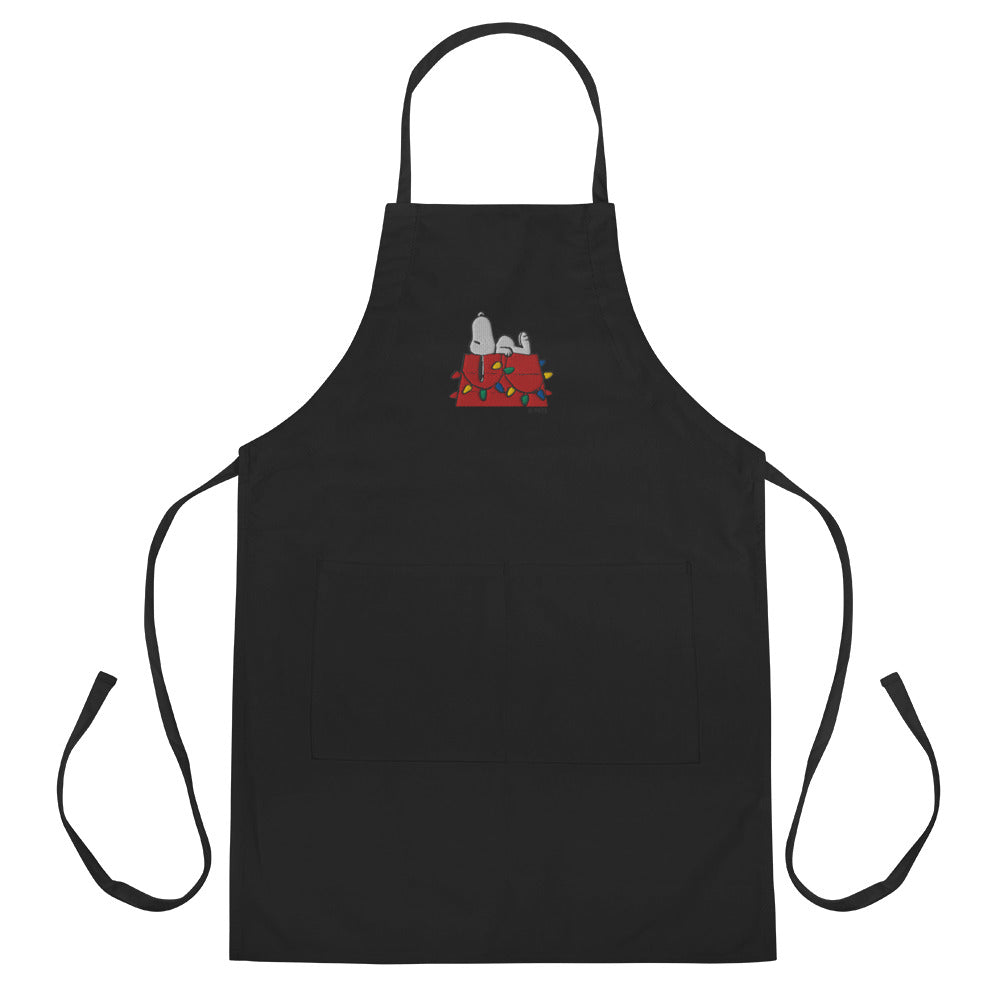 White kitchen apron featuring an embroidered graphic of Snoopy resting on his red doghouse
